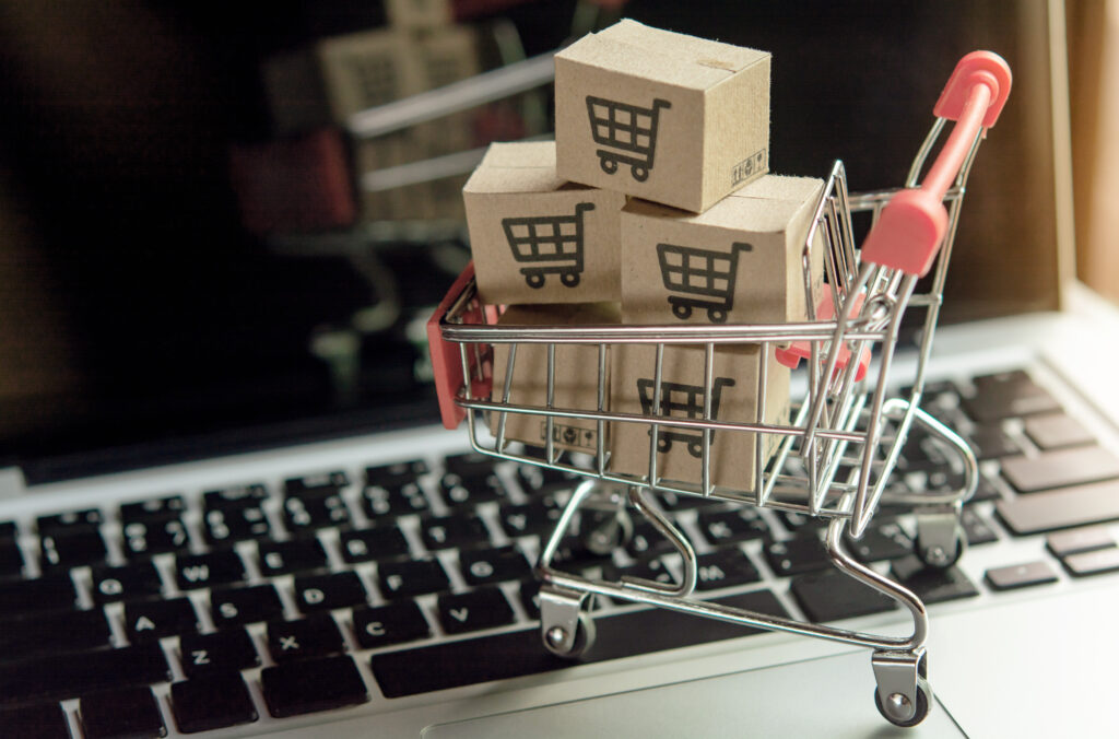 Image is of a small shopping cart being full of items in front of a keyboard to depict an impulse to spend, spend, spend as an individual with ADHD. This blog article looks at some examples of adult behaviours in individuals with ADHD, written by neuro affirming counsellor and psychotherapist Amanda Reynolds.