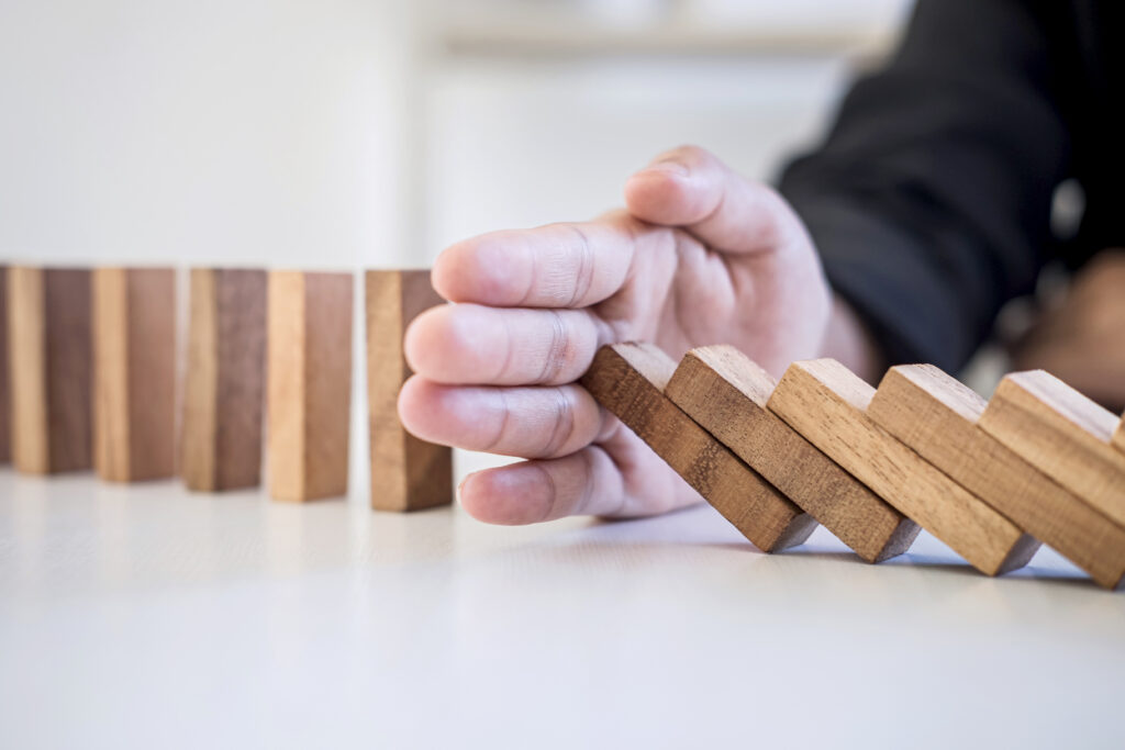 Image is of a hand interrupting a row of falling dominos to depict interrupting others often as an individual with ADHD may be rooted in impulsivity This blog article looks at some examples of adult behaviours in individuals with ADHD, written by neuro affirming counsellor and psychotherapist Amanda Reynolds.